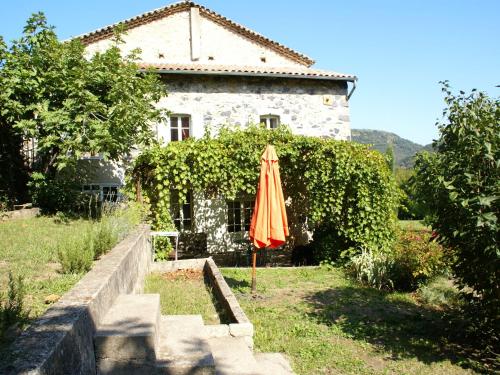 an orange umbrella sitting in front of a building at Lovely house with grass garden shared swimmingpool next to the river Ard che in Lalevade-dʼArdèche