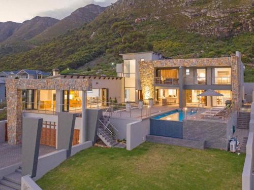 a house with a swimming pool in front of a mountain at Waterstone Villa in Hermanus