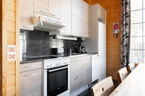 uma cozinha com fogão forno superior ao lado de uma mesa em Himos Villa Jimi Hendrix, Ei lisäkuluja! em Jämsä