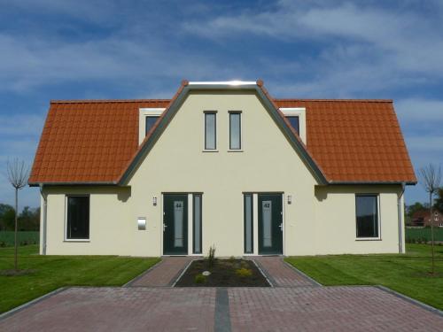 ein weißes Haus mit orangefarbenem Dach in der Unterkunft Holiday home in Wietzendorf in the L neburg Heath with a view of the countryside in Wietzendorf