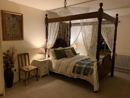 1 dormitorio con cama con dosel y silla en Drimnatorran Farm Lodge, en Estroncia