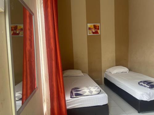 two beds in a small room with a mirror at OYO 93850 Njy House Syariah in Pekanbaru