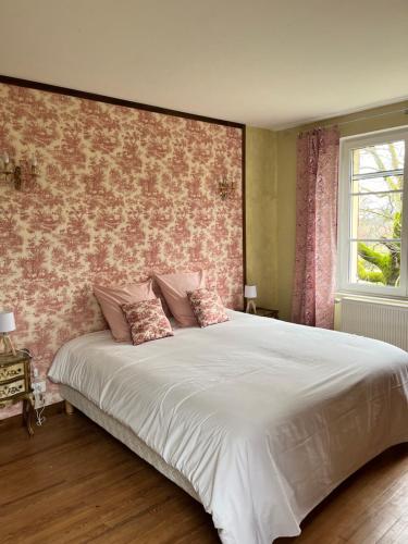 - une chambre avec un grand lit et du papier peint floral rose dans l'établissement Gîte Baccara 4 étoiles, à Gondrin