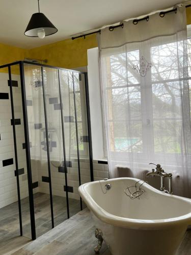 une salle de bain avec une baignoire et une fenêtre dans l'établissement Gîte Baccara 4 étoiles, à Gondrin