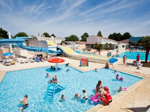 um grupo de pessoas em uma piscina em um parque aquático em Mobil-home a louer dans un camping **** proche de la mer et forêt em Saint-Jean-de-Monts