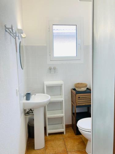 une salle de bain avec un lavabo et des toilettes et une fenêtre dans l'établissement Punta di Mare, appartements comme sur un bateau, à Linguizzetta