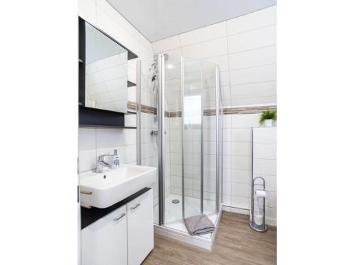 a white bathroom with a sink and a shower at Holiday home Villa Maiwaldo in Spieka-Neufeld