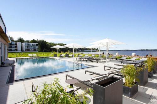una piscina con sedie a sdraio e ombrelloni di Apartments in the MAREM RITZ Marina Resort Waren an der M ritz a Waren