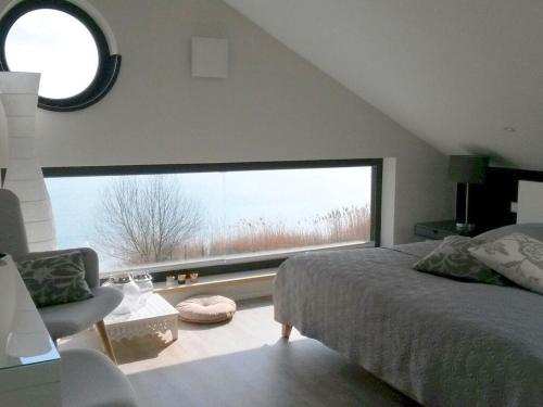 een slaapkamer met een bed en een groot raam bij Holiday house house on Mühlfeldsee in Löbnitz