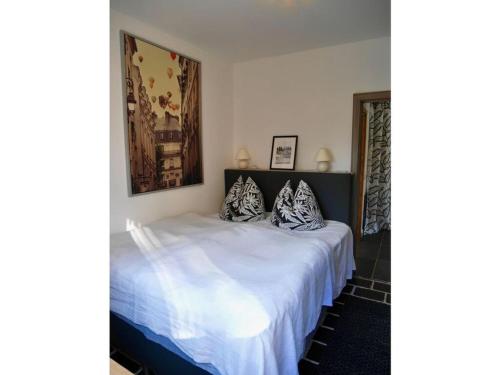 een slaapkamer met een wit bed met kussens erop bij Holiday apartment wellness & relaxation in Wunsiedel
