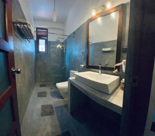 a bathroom with a sink and a toilet and a mirror at Jumelle Residence in Horetuduwa