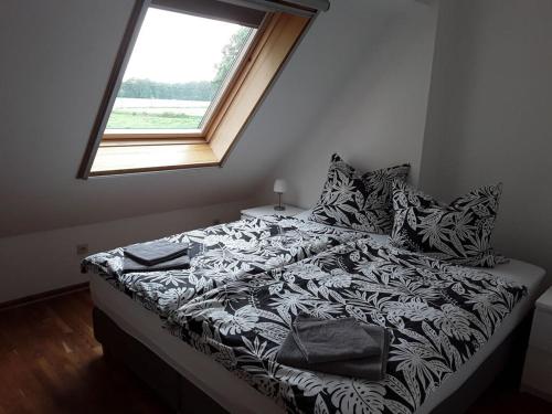 ein Bett mit einer schwarzen und weißen Bettdecke und einem Fenster in der Unterkunft Holiday apartment Aufderhaar in Ostbevern