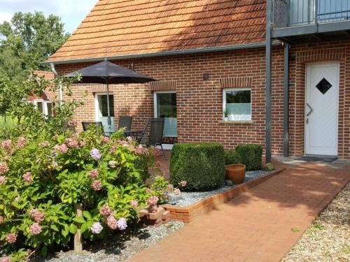 a brick house with an umbrella and some flowers at Holiday apartment Aufderhaar in Ostbevern