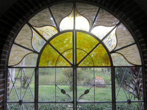 a stained glass window with a view of a yard at La Posada del Cucú in Salento