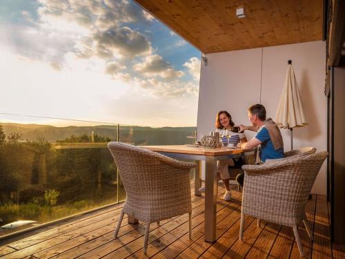 um homem e uma mulher sentados numa mesa no convés em Mosel Sky Lounge with loggia & panoramic view em Kenn