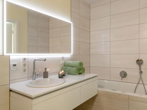 uma casa de banho com um lavatório, um espelho e uma banheira em Mosel Sky Lounge with loggia & panoramic view em Kenn