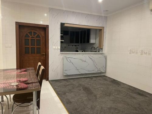 eine Küche mit einem Tisch, einem Tisch und einer Tür in der Unterkunft شاليه سهم in Khobar