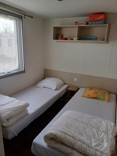 deux lits dans une petite pièce avec une fenêtre dans l'établissement Mobil-home a louer dans un camping **** proche de la mer et forêt, à Saint-Jean-de-Monts