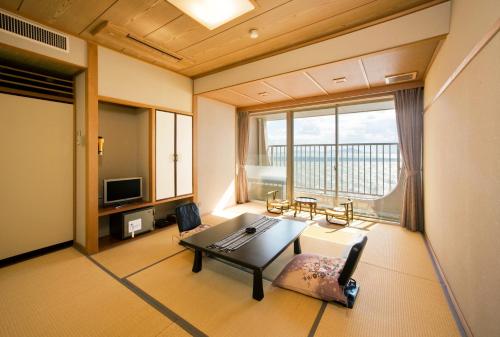 sala de estar con mesa y ventana grande en Ako Onsen Shokichi, en Ako