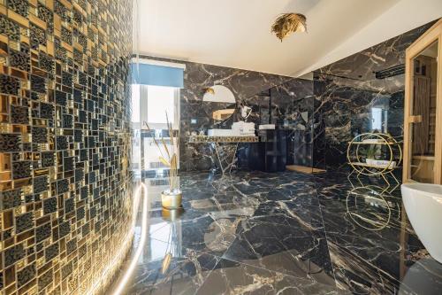 baño con paredes de mármol negro y lavabo en Étoiles Luxury guest house Resort, en Palmi