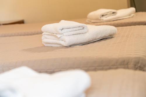 three white towels are stacked on a bed at Four Seasons Hotel in Athens