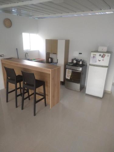 a kitchen with a counter and two chairs and a refrigerator at Casa Hospedaje los Delfines en playa tortugas in Tortuga