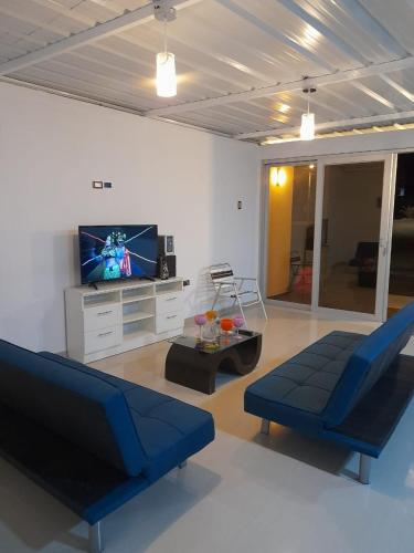 sala de estar con 2 sillas azules y TV en Casa Hospedaje los Delfines en playa tortugas, en Tortuga