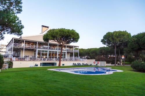 a building with a swimming pool in the grass at Hotel Nuevo Portil Golf in El Rompido