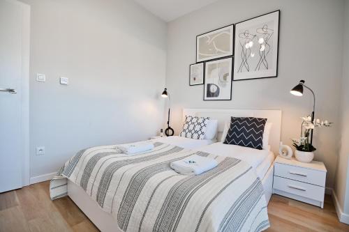 een witte slaapkamer met een bed met een gestreepte deken bij Apartamenty Laguna Beskidów - A04 in Zarzecze