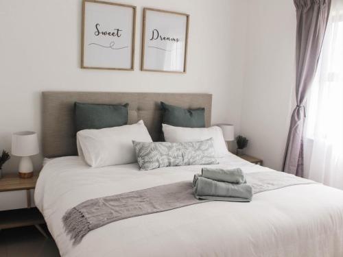 a bedroom with a large white bed with three pictures on the wall at Modern 2 bedroom apartment close to shops & beach in Gordonʼs Bay