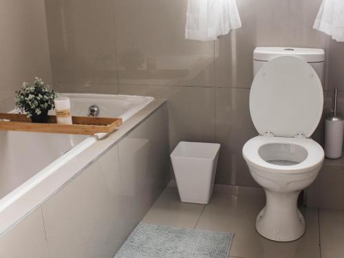 a bathroom with a toilet and a sink and a tub at Modern 2 bedroom apartment close to shops & beach in Gordonʼs Bay
