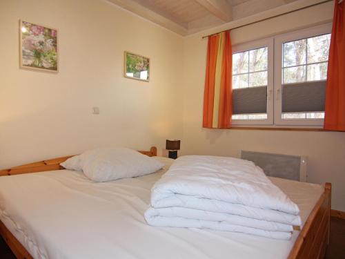 a bedroom with a bed with white sheets and two windows at Semi-detached house Strandhaus I, Trassenheide in Trassenheide