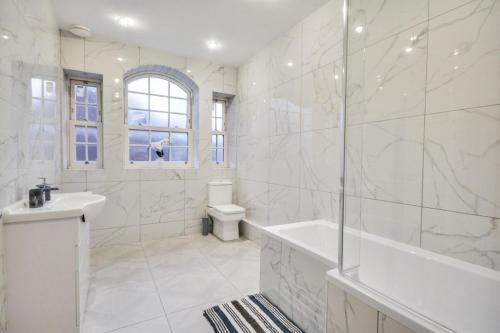 a white bathroom with a tub and a sink at 3 Bed Apartment in Wigan in Wigan