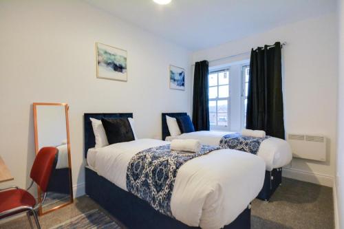 a bedroom with two beds and a window at 3 Bed Apartment in Wigan in Wigan