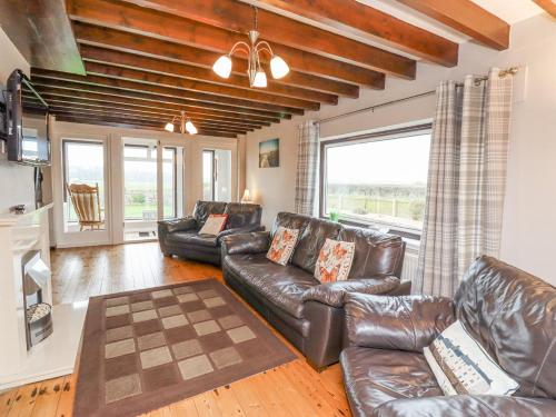 a living room with leather furniture and a large window at Whitestacks in Bamburgh