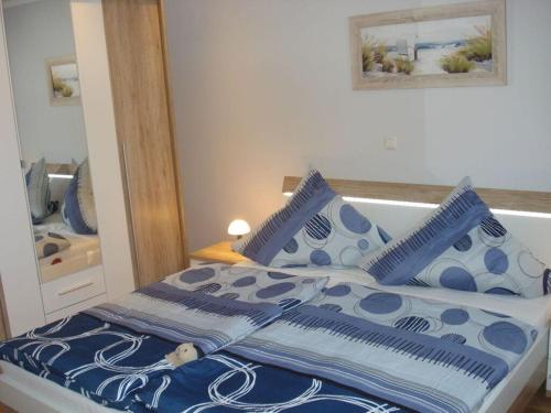 1 cama con almohadas azules y blancas y espejo en Holiday home Klinger, en Todendorf auf Fehmarn