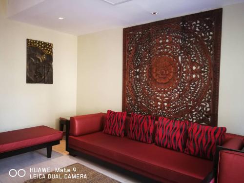 a living room with a red couch and a large painting at Hua Hin Blue Lagoon in Cha Am