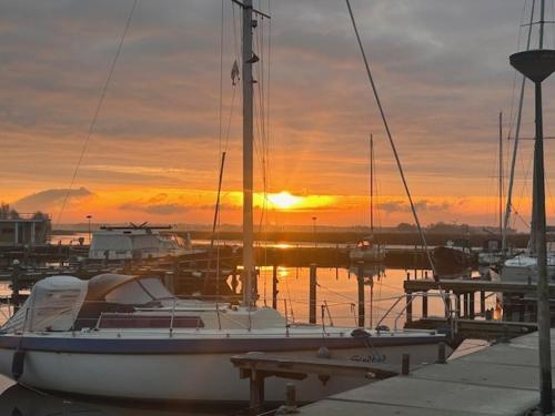 a boat is docked at a dock with the sunset at Minicamping Marina Warns in Molkwerum