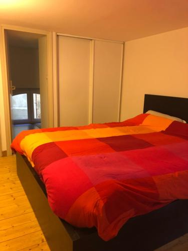 - une chambre avec une couette rouge et orange sur un lit dans l'établissement Appartement hyper centre ville Toulouse, à Toulouse