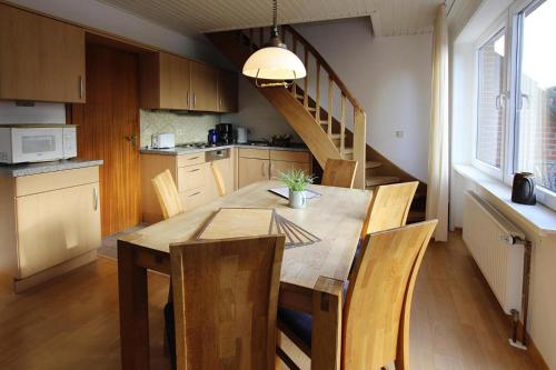 a kitchen with a wooden table with chairs and a staircase at Apartment house Katharina Westerland in Westerland (Sylt)