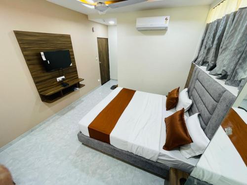 a bedroom with a bed and a tv on the wall at Hotel Nova Blue in Ahmedabad