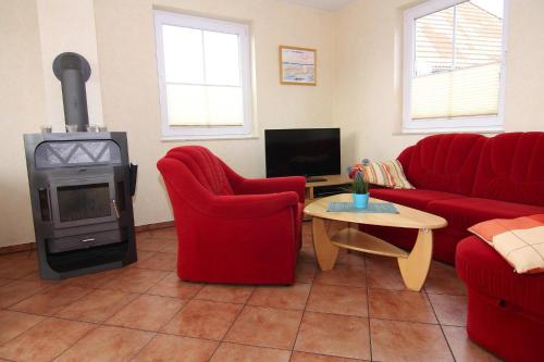 a living room with red chairs and a wood stove at Semi detached house Kuehlungsborn in Kühlungsborn