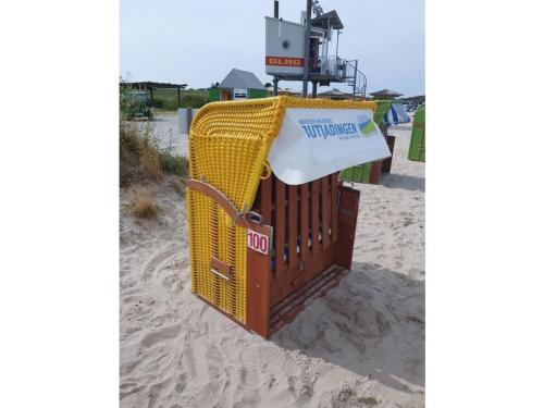 a yellow wicker trash can on the beach at Holiday home Tim Paul in Hoddersdeich