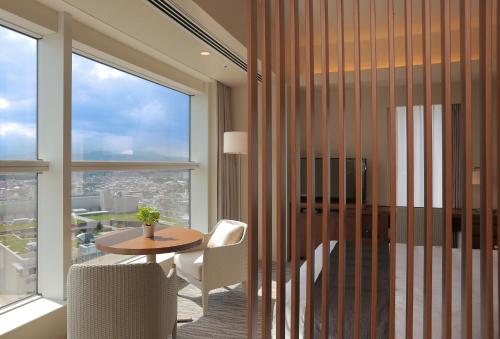 a room with a table and chairs and a large window at Odakyu Hotel Century Sagami Ono in Sagamihara