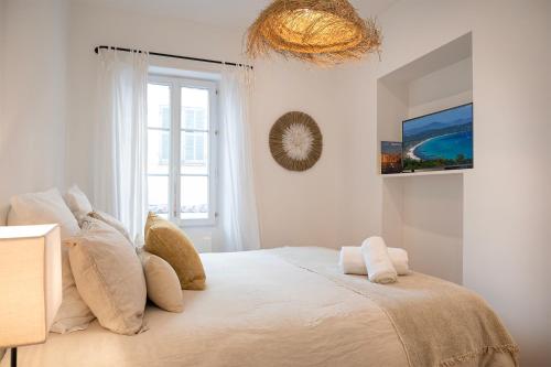 a bedroom with a large white bed with a window at La Tropézienne - appartement au cœur du village in Saint-Tropez