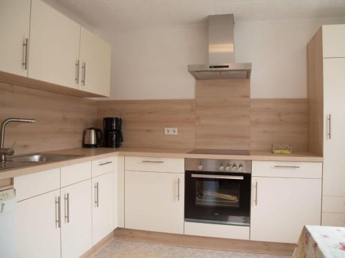 cocina con armarios blancos, fregadero y horno en Spacious Holiday Home in Ulmen near the centre, en Ulmen