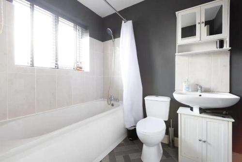 a bathroom with a white tub and a toilet and a sink at Large 5-Bed House in Leeds Fits 10 Free Parking in Leeds
