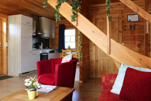 Il dispose d'une cuisine et d'un salon avec des chaises rouges et un escalier. dans l'établissement Blockhouse in the Fuchsbau Bad Sachsa, à Bad Sachsa