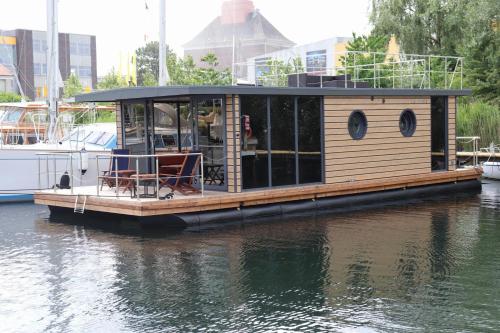 Houseboat Leni Flensburg في فلنسبورغ: منزل صغير على رصيف في الماء