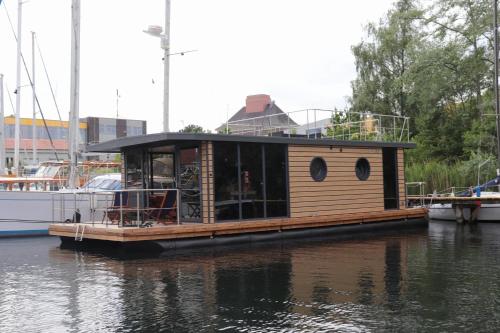 Houseboat Leni Flensburg في فلنسبورغ: منزل صغير على رصيف في الماء